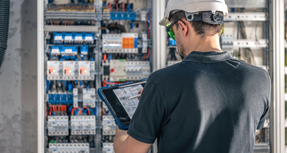 Electrical engineer inspecting and testing an industrial control panel during a maintenance check